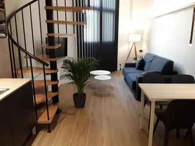 a living room with a blue couch and a spiral staircase at SLEEP TURIA LLIRIA in Lliria