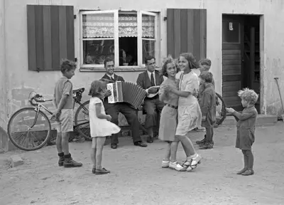 a group of children standing around a woman playing an accordion at SLEEP TURIA LLIRIA in Lliria