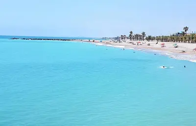 a beach with people swimming in the blue water at Moncofa Beach in Moncófar