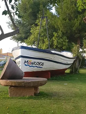 a boat sitting on the grass next to a bench at Moncofa Beach in Moncófar