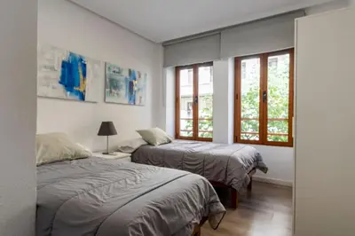 a bedroom with two beds and two windows at Garden Turia Downtown in Valencia
