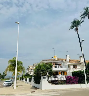 a white house with a palm tree in front of it at Valencia Sol y Playa in Sagunto
