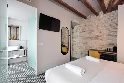 a bedroom with a white bed and a brick wall at YOU & CO. Quart Boutique in Valencia