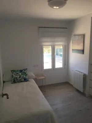 a white bedroom with a bed and a window at Casa Ferrada in Burriana