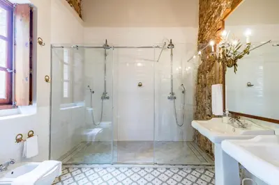 a bathroom with a glass shower and two sinks at Alquería Calatrava B&B in Burriana