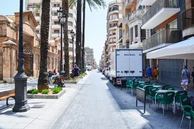 a street with chairs and a truck parked on the street at VIRGEN APARTAMENT HOTEL in Cullera