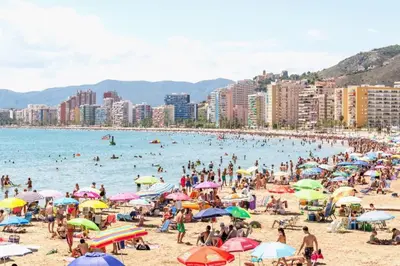 a crowd of people on a beach with umbrellas at VIRGEN APARTAMENT HOTEL in Cullera