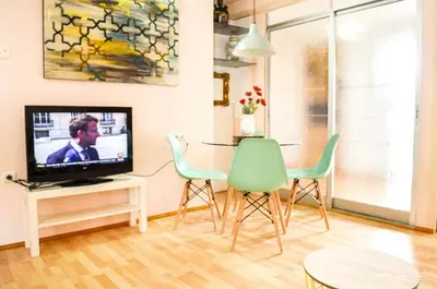 a living room with chairs and a tv and a table at VIRGEN APARTAMENT HOTEL in Cullera
