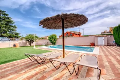 a patio with two chairs and an umbrella next to a swimming pool at Family Villa in Benifayó with Year-Round Private Pool in Benifayó