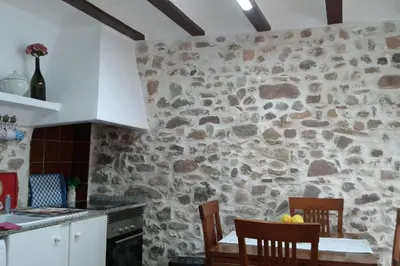 a stone wall in a kitchen with a table and chairs at Rosita Casa Rural in Estivella