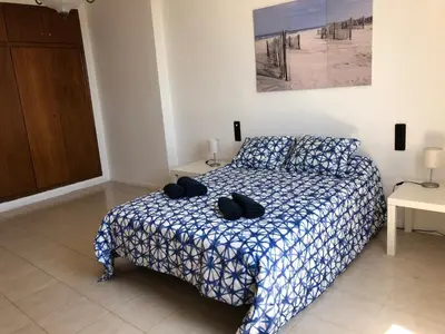 a bedroom with a bed with a blue and white comforter at Apartamento Puerto de Sagunto Playa in Puerto de Sagunto