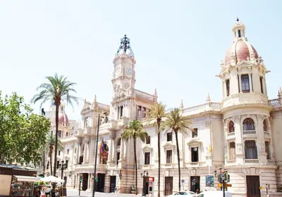 a building with a clock tower and palm trees at ApartUP Central Market II in Valencia