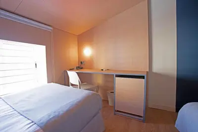 a bedroom with a bed and a desk and a window at Olympia Consul del Mar in Valencia