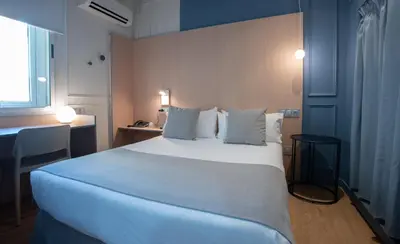 a bedroom with a large white bed and a desk at Olympia Consul del Mar in Valencia