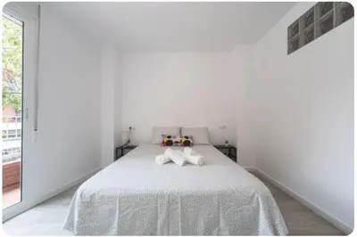 a white bedroom with a bed with two towels on it at Islas Canarias Apartment in Valencia