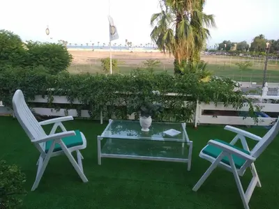 two chairs and a glass table on a lawn at Apartamento con terraza y vistas al mar in Burriana