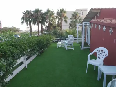 a patio with white chairs and green grass at Apartamento con terraza y vistas al mar in Burriana