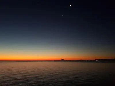 a sunset over the water with the moon in the sky at Faro de Cullera I in Faro de Cullera
