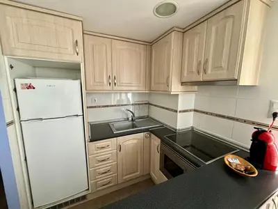 a kitchen with wooden cabinets and a white refrigerator at Faro de Cullera I in Faro de Cullera