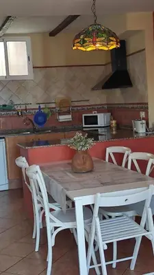 a kitchen with a table with white chairs and a kitchen at La Media Luna in Segorbe