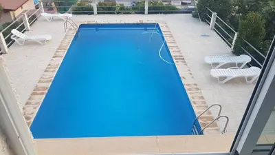an empty swimming pool with two chairs and two tables at Calicanto House & Pool in Torrent