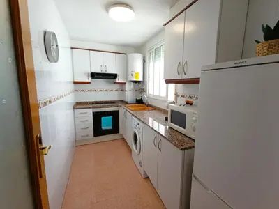 a kitchen with white cabinets and a white refrigerator at Seabreeze Lighthouse Apartment in Faro de Cullera