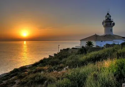 a lighthouse sitting on top of a hill next to the ocean at Seabreeze Lighthouse Apartment in Faro de Cullera