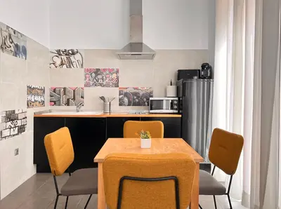 a kitchen with a table and chairs and a refrigerator at Maritime Apartamentos Cabañal in Valencia