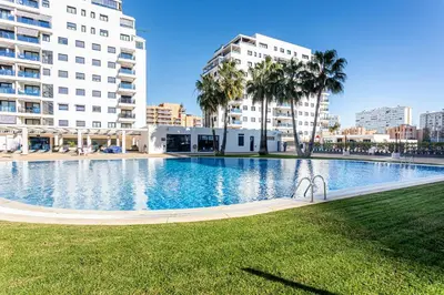 a large swimming pool in a city with tall buildings at Playa Valencia Residencial Sol y Mar Terraza con Vistas y Parking in Playa Pobla de Farnals