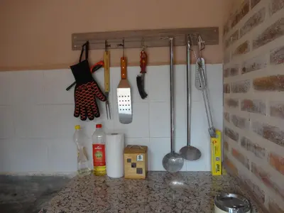 a kitchen counter with utensils hanging on a wall at LAS PALOMAS, appartement 3 chambres avec piscine in Turís