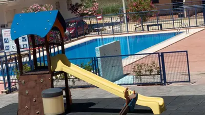 a yellow slide in front of a swimming pool at Apartamento Playa Moncofar - Xilxes in Moncófar