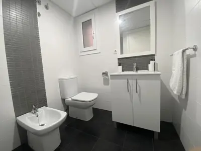 a white bathroom with a toilet and a sink at LUJOSO apartamento- PLAYA Canet Berenguer in Canet de Berenguer