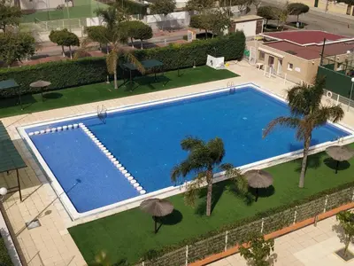 an overhead view of a swimming pool with palm trees and umbrellas at LUJOSO apartamento- PLAYA Canet Berenguer in Canet de Berenguer