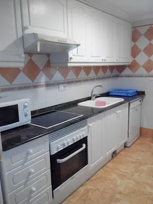 a kitchen with white cabinets and a sink and a microwave at RELAX, MAR Y MONTAÑA in Tavernes de Valldigna
