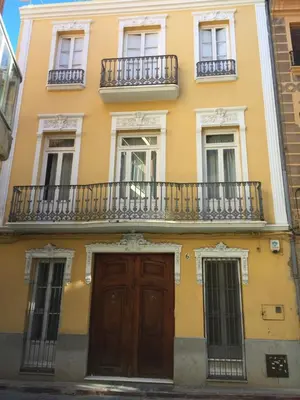 a yellow building with a wooden door and balconies at Casa Modernista 
