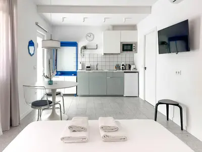a white kitchen with a table and a table and chairs at Apartamentos Navío in Valencia