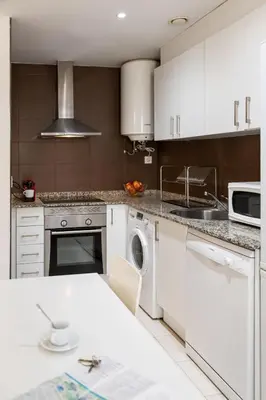 a kitchen with white cabinets and a sink and a dishwasher at Hideout 26 in Valencia