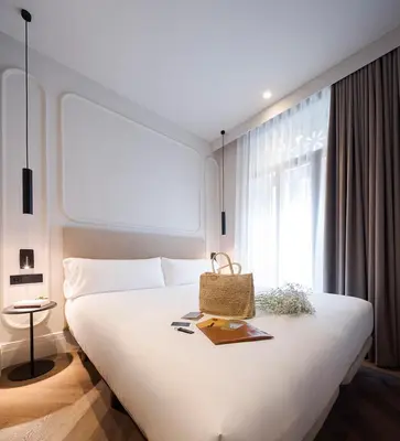 a bedroom with a large white bed and a window at Room Mate Oliveira - City Centre, Valencia in Valencia