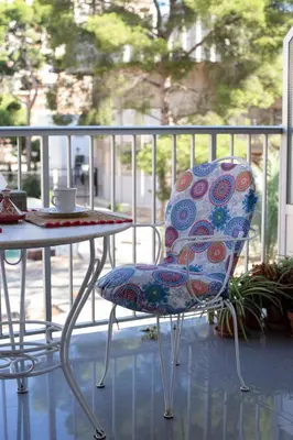 a chair sitting next to a table on a balcony at Bonito apartament a 3 minutos de la playa in Cullera