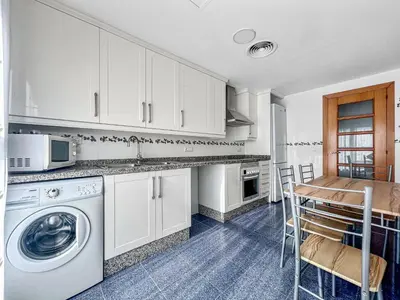 a kitchen with white cabinets and a table and a washing machine at NEW! Apartamento Ciudad de las Artes in Valencia