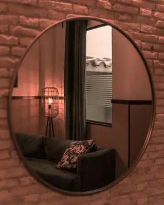 a mirror on a wall with a couch and a window at Hografic Hotel in Valencia