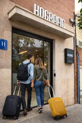 a man and woman walking into a hotel with their luggage at Hografic Hotel in Valencia