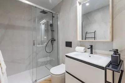 a white bathroom with a shower and a sink at Goerlich by Alma Suites in Valencia