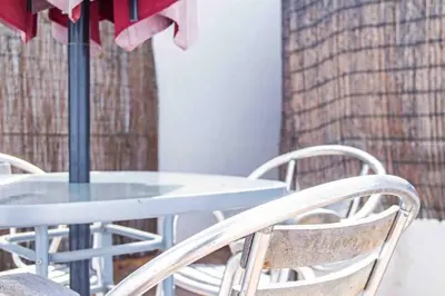 a blue table with white chairs and an umbrella at Acogedor Dúplex con terraza interior en la playa in Valencia