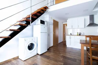 a white kitchen with a staircase and a washing machine at Acogedor Dúplex con terraza interior en la playa in Valencia