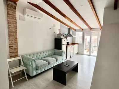 a living room with a green couch and a table at Estudio para parejas con terraza en la playa in Valencia
