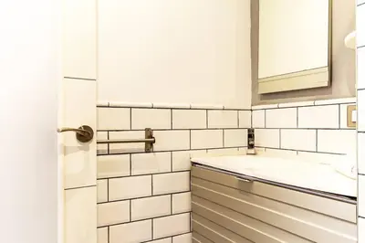 a white tiled bathroom with a sink and a mirror at Apartamento con terraza privada cerca de la playa in Valencia