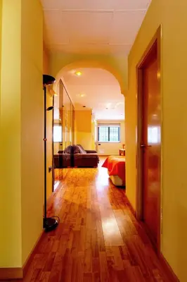 a hallway with a room with yellow walls and wooden floors at Estudio para parejas con WIFI en la playa in Valencia