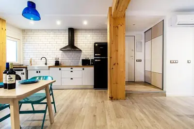 a kitchen with a table and a black refrigerator at Chic y renovado loft en la playa in Valencia