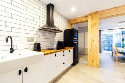 a kitchen with white cabinets and a black refrigerator at Chic y renovado loft en la playa in Valencia